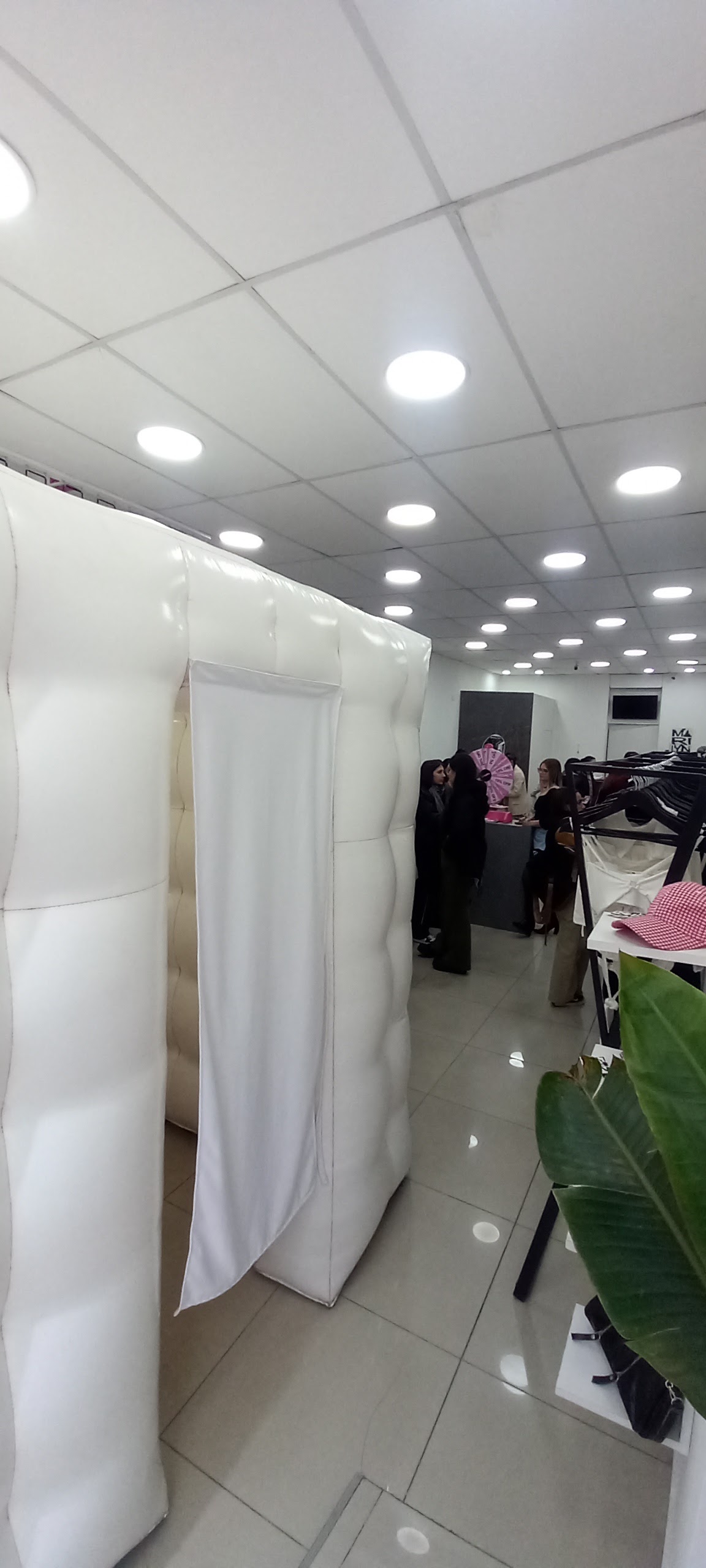 Realistic party photograph of stylish guests holding cute props and instant printed photo strips at a wedding reception party with glowing purple and magenta inflatable photo booth in background, Paraná event venue, warm party vibe.